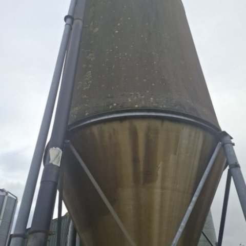 Een silo op een stalen frame waar twee buizen langs omlaag lopen.