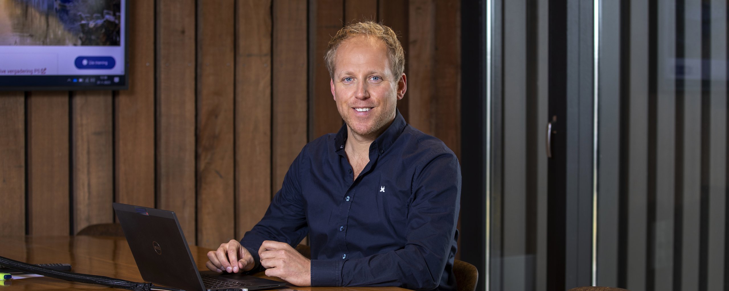 Een man zit achter een laptop te werken.